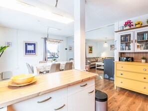 A modern kitchen with a wooden countertop, white cabinets, and a dining area with a table and chairs. - Kellerwald by Interhome (Frankenau)