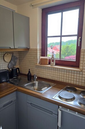 Een koelkast, kookgerei, borden en bestek