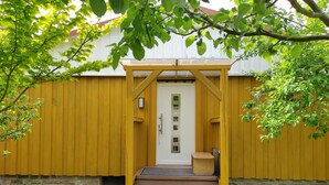 Eine Holztür mit einer kleinen Veranda, die zu einem weißen Gebäude führt.
