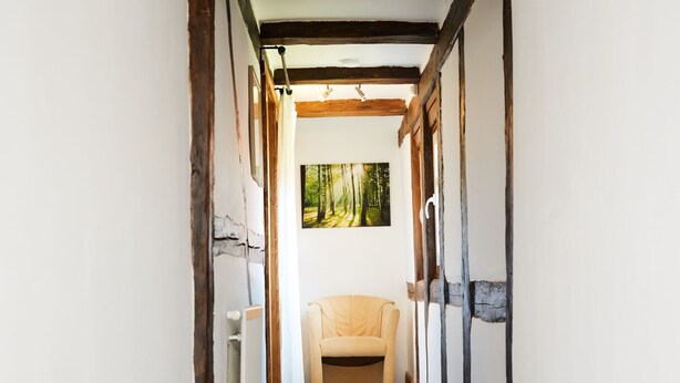 A narrow hallway with exposed wooden beams, a radiator, and a window with a forest view. - Fachwerkhaus mit Garten, Grill und Terrasse by Interhome (Behringen)