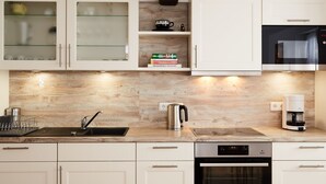 A modern kitchen with white cabinetry, a built-in oven, a coffee maker, and a kettle. - Fachwerkhaus mit Garten, Grill und Terrasse by Interhome (Behringen)