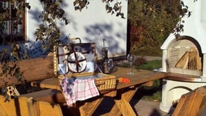 Un tavolo da pranzo in legno all'aperto con apparecchiatura da picnic, inclusi un cesto, piatti e bicchieri da vino.