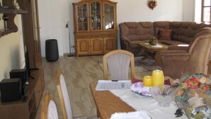 Un soggiorno con un divano marrone, un mobiletto in legno e un tavolo da pranzo con sedie.