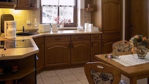 Cucina con mobili in legno, lavello, macchina del caffè e finestra vista alberi.