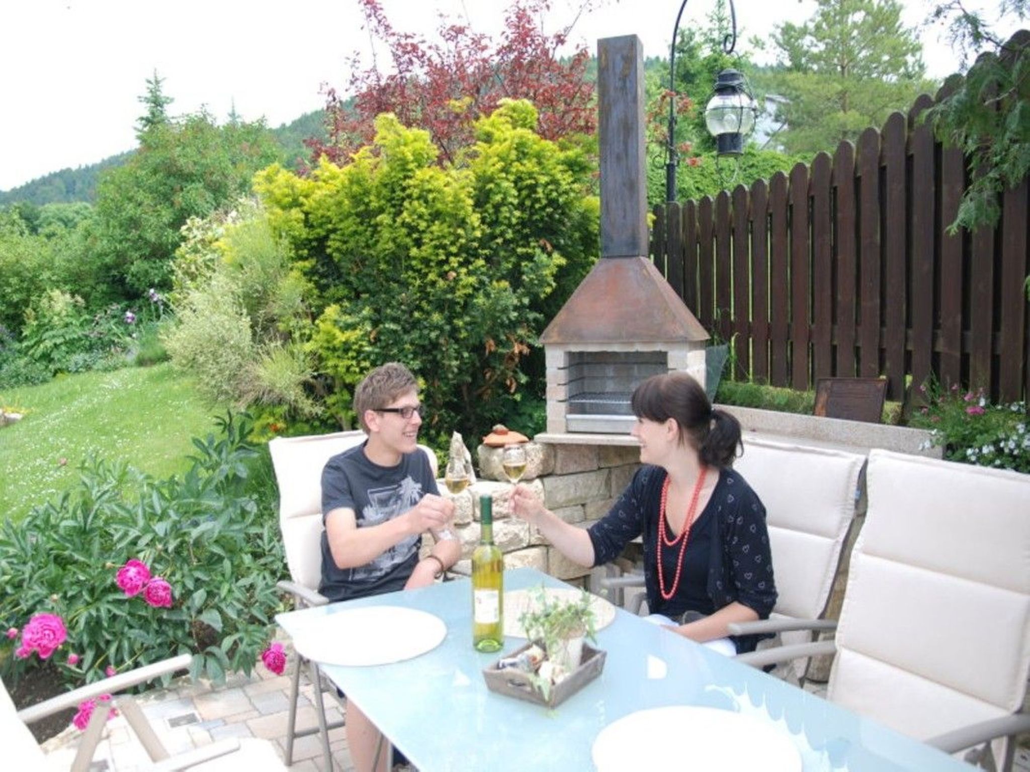Eine Terrasse im Freien mit Tisch, Stühlen und einem Pizzaofen.