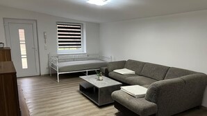 Ein modernes Wohnzimmer mit einer grauen Couch, einem kleinen Couchtisch und einem Fenster mit Jalousien.