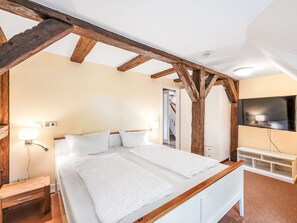 A bedroom with a wooden ceiling, a bed with white bedding, a bedside table, a TV, and a wardrobe. - Reethaus Mertinat ''For Ten'' mit Meerblick by Interhome (Gollwitz (Insel Poel))
