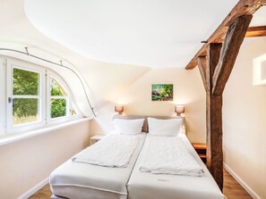 A bedroom with a curved ceiling, a bed with white bedding, two bedside lamps, and a window with a view of greenery. - Reethaus Mertinat ''For Ten'' mit Meerblick by Interhome (Gollwitz (Insel Poel))