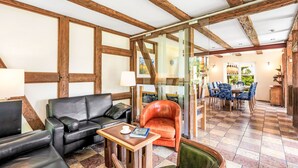Une pièce avec un plafond en bois, un canapé en cuir noir, une table basse en bois et un fauteuil vert.