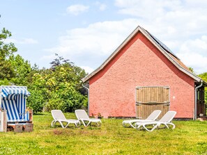 A red barn with a wooden door, surrounded by a grassy area with white lounge chairs. - Reethaus Mertinat ''For Ten'' mit Meerblick by Interhome (Gollwitz (Insel Poel))
