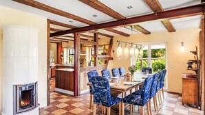 Un espace repas doté d’un plafond en bois, d’une cheminée et d’un sol à carreaux.