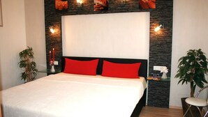 A modern bedroom with a large bed, red pillows, a stone accent wall, and wall-mounted lights. - Ferienwohung 1 - Erdgeschoss by Interhome (Zempin)