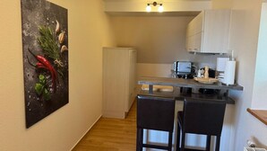 A compact kitchen with a refrigerator, microwave, and a small dining area with two chairs. - Apartment Karpfen 4 by Interhome (Neukloster)