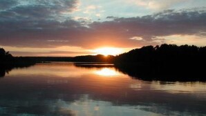 A calm lake at sunset with a silhouette of trees on the horizon. - Mobilheim Zweiundvierzig in Lychen by Interhome (Lychen)