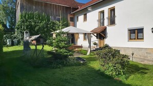 Ein zweistöckiges Haus mit rotem Ziegeldach, weißer Fassade und einem kleinen Balkon.