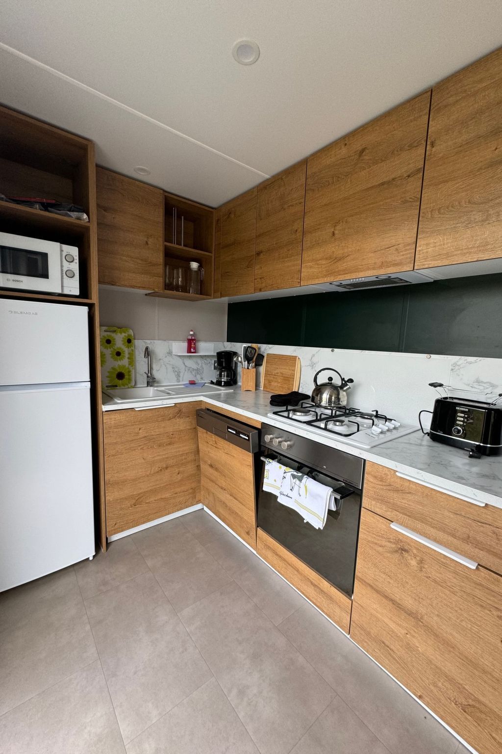 Een moderne keuken met houten kastjes, een ingebouwde magnetron, een gasfornuis en een vaatwasser.