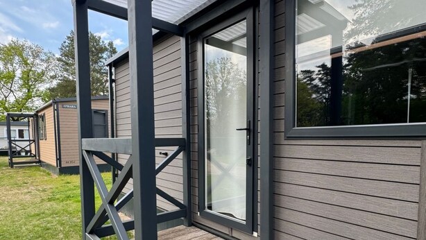 Una casa moderna con un porche cubierto, ventanas amplias y un césped bien cuidado.