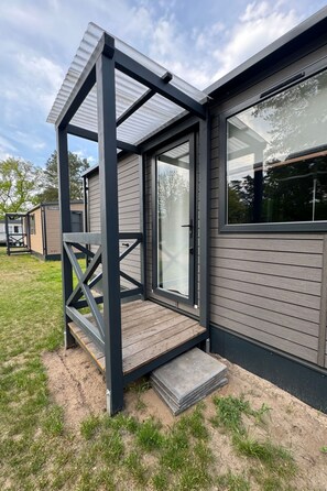 Une maison moderne dotée d’un porche abrité, de grandes fenêtres et d’une pelouse bien entretenue.