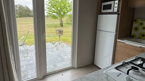 Una cocina moderna con estufa a gas, armarios blancos y puerta corrediza de vidrio que da a un patio.