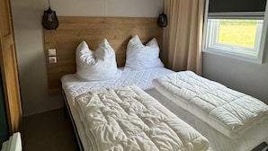 Una habitación de hotel con una cama, un ventanal con cortinas y un cabecero de madera.