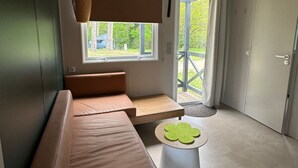 Una sala de estar moderna con un sofá modular, una mesita redonda y un ventanal con vistas al exterior.