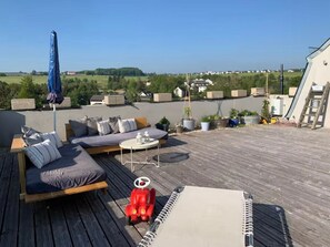 A rooftop deck with a sofa, a small table, and a red toy car. - Leo's Loft by Interhome (Halsenbach)