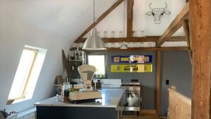 Une cuisine avec des poutres en bois, un îlot central et un luminaire suspendu.