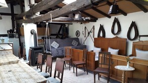 Un interior rústico con una mesa de comedor, sillas de madera, un sofá y una pequeña mesa redonda con un jarrón.