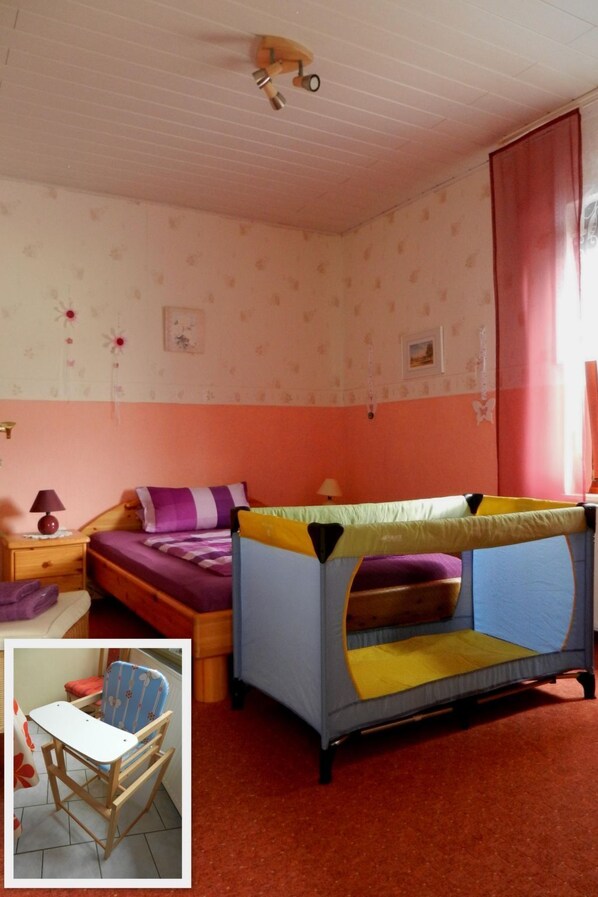 Un dormitorio con literas, una mesita, una silla y un ventanal con cortinas.
