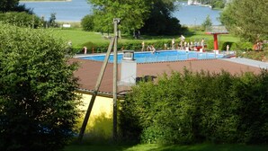 A swimming pool with diving platforms and a lifeguard tower, surrounded by lush greenery and a lake view. - im Teutoburger Wald by Interhome (Schieder-Schwalenberg)