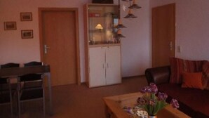 A living room with a wooden cabinet, a dining table, and a sofa. - Erzgebirge by Interhome (Johanngeorgenstadt)