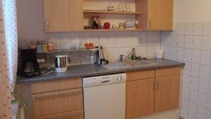 A compact kitchen with wooden cabinets, a built-in dishwasher, a coffee maker, and a sink. - Erzgebirge by Interhome (Johanngeorgenstadt)