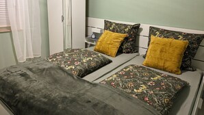 Ein Schlafzimmer mit einem Bett, zwei Kissen, einem Nachttisch und einem Kleiderschrank.
