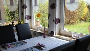 Ein Esstisch mit einer weißen Tischdecke, zwei Stühle und einer Blumenvase.