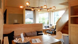 A cozy cabin interior with a wooden dining table, a sofa with cushions, a small kitchen area, and a staircase leading to an upper level. - Vacation home "Henk" by Interhome (Alt Jassewitz)
