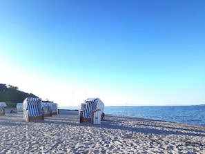 A beach with striped beach chairs and umbrellas, a clear sky, and calm sea. - Vacation home "Henk" by Interhome (Alt Jassewitz)