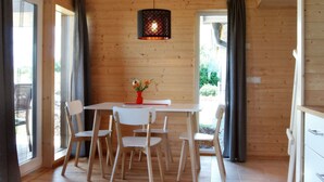 Un intérieur en bois avec une table et des chaises, un luminaire suspendu et de grandes fenêtres.
