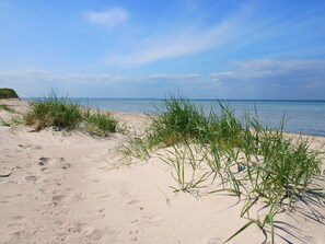 A sandy beach with green grass in the foreground and a calm sea in the background. - "Feldrain" by Interhome (Alt Jassewitz)