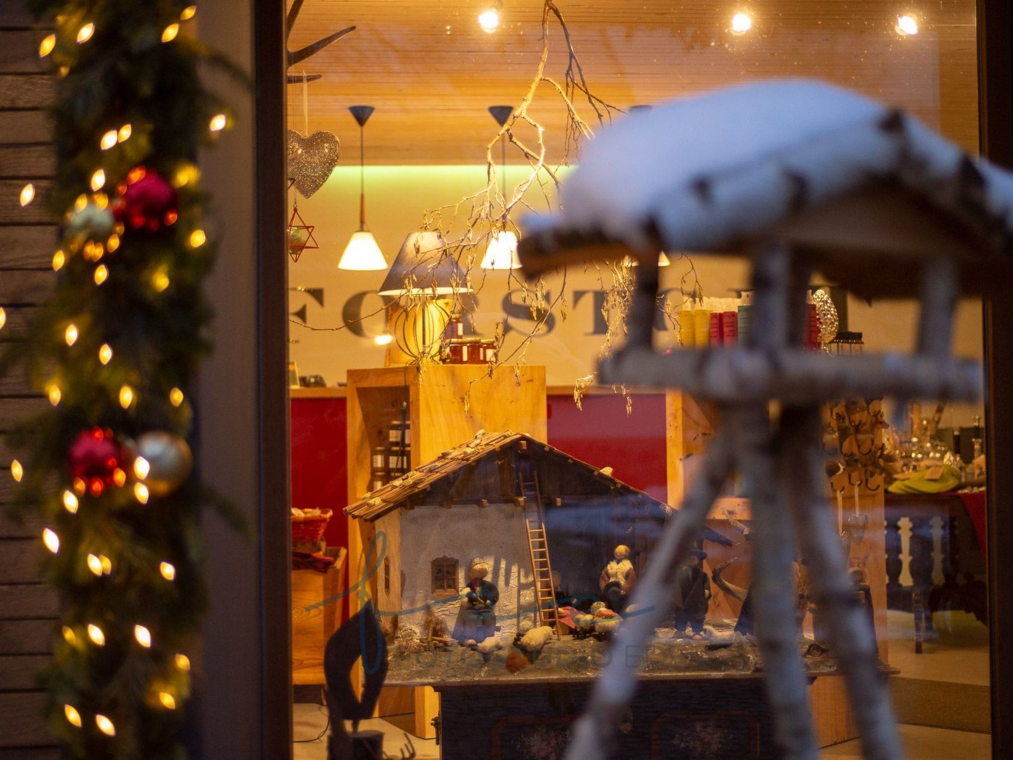 Un intérieur chaleureux avec un plancher en bois rustique, une petite maison miniature et un sapin de Noël.