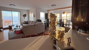 Ein modernes Wohnzimmer mit einer Couch, einem Essbereich und einer Küche mit Spüle und dekorativen Glasflaschen.