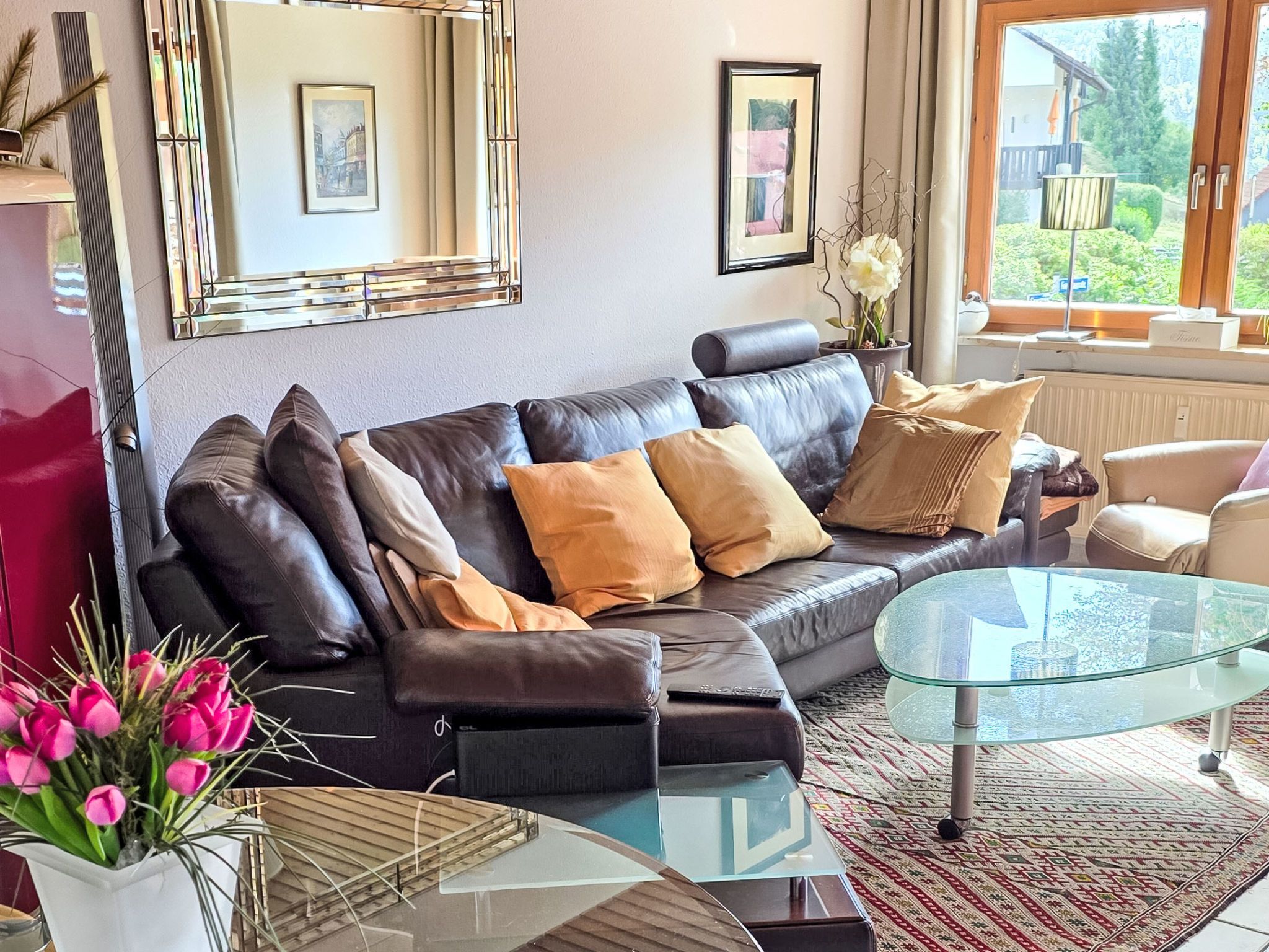 A modern living room with a leather sofa, a glass coffee table, and a patterned rug.