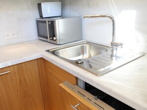 A kitchen with a stainless steel sink, a microwave, and wooden cabinets. - Kuschelnest Oase by Interhome (Todtmoos)