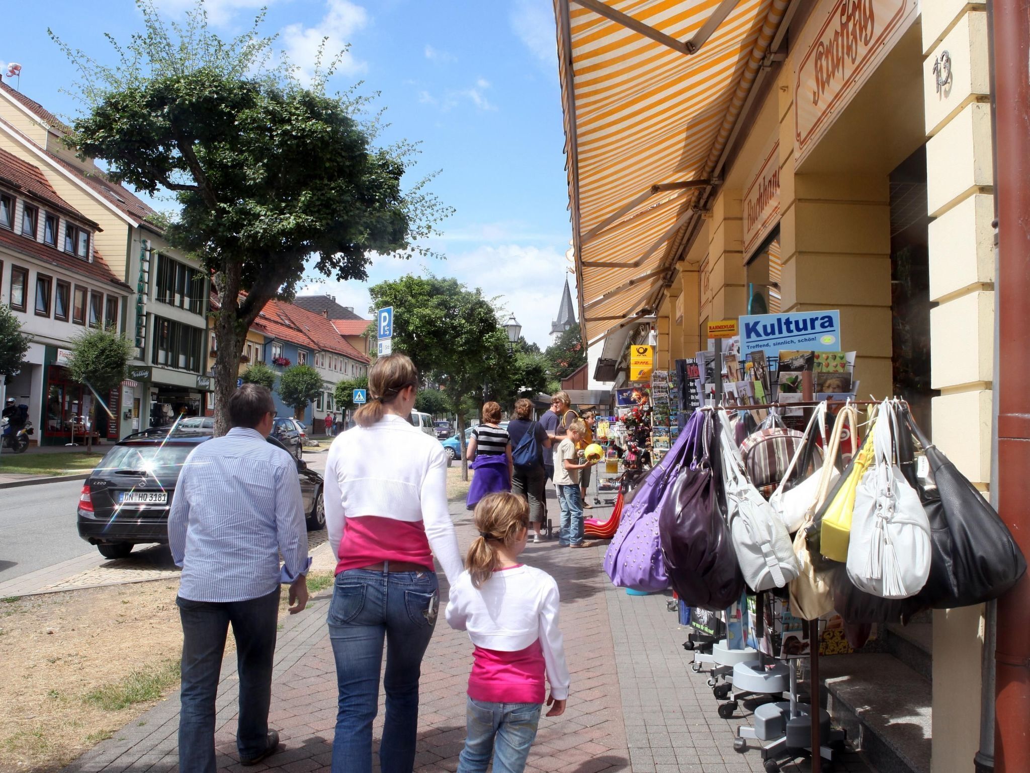 Een straatbeeld met een rij winkels, waaronder een zichtbaar bord met 'Kultur'.