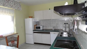 Uma cozinha pequena com armários brancos, micro-ondas, pia e fogão.