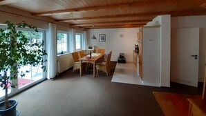 A dining area with a wooden table and chairs, a potted plant, and a view of the outdoors through large windows. - Fewo Stricker 31 by Interhome (Walkenried)