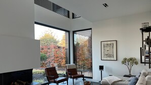 A modern living room with a fireplace, large windows, and a cozy seating area. - Modernes Einfamilienhaus by Interhome (Fahrland)
