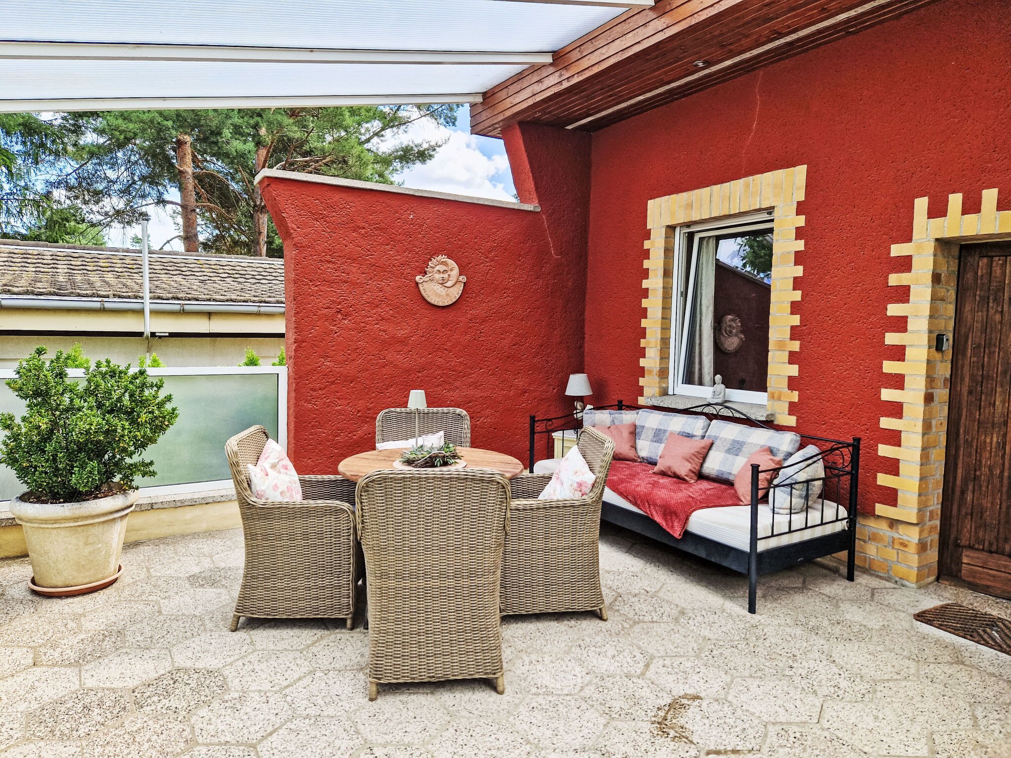 Un bâtiment rouge doté d’un balcon, de meubles en osier et d’une fenêtre.