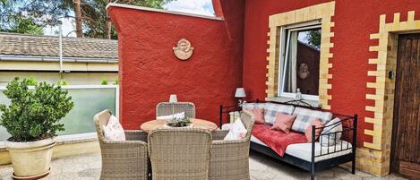 Un bâtiment rouge doté d’un balcon, de meubles en osier et d’une fenêtre.