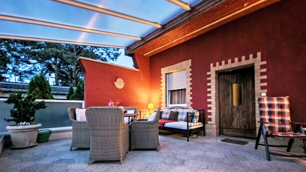 Eine Außenpatio-Terrasse mit Korbmöbeln, einem Tisch und einer Couch.