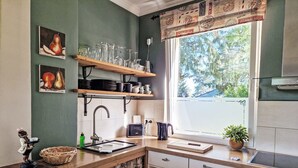 Eine Küche mit Fenster, Spüle, Herd und Regalen mit Gläsern.